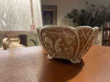 Ornate ceramic bowl with squirrel design on a wooden surface.
