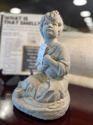 A stone statue of a seated child holding a book, with detailed facial features.