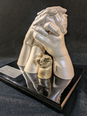 Family memorial casting, Pearl and champagne casts displayed on a black piano finish plaque.