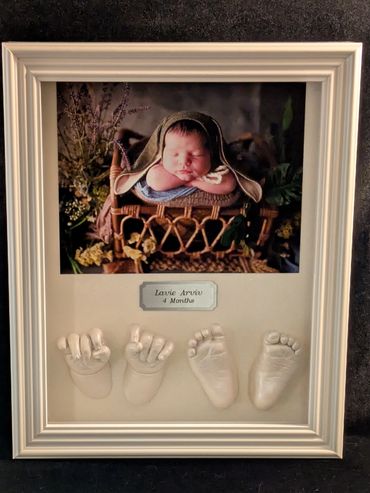 White shadow box displaying a baby photo  with baby hand and foot casting