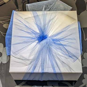 Signature packaging of Forget Me Not 3D Casting - two blue tulle bows on white box