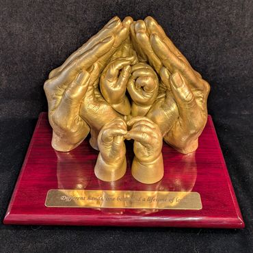 Gold coloured 4 person family sculpture displayed on a red base with gold name plate 