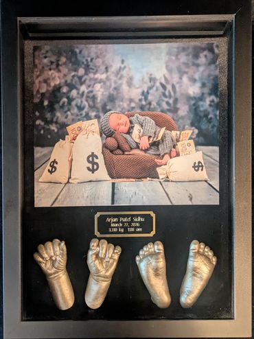 Black shadow box displaying a baby photo  with baby hand and foot casting