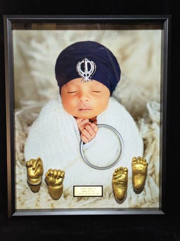 Black shadow box displaying a baby photo  with baby hand and foot casting