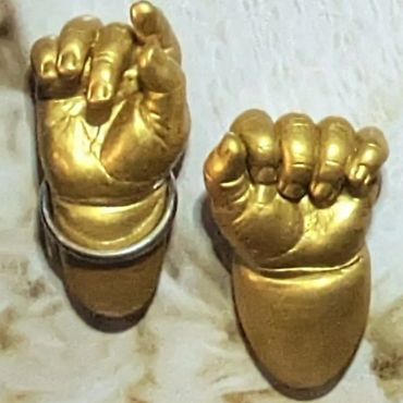 Baby hand casts coloured in vintage gold and one wearing a silver kada