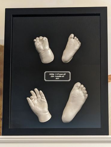 Pearl coloured hand and foot casting of 8 month old and 2 yrs old siblings in a black shadow box