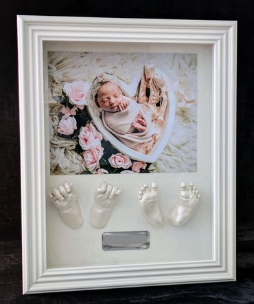 White shadow box displaying a baby photo  with baby hand and foot casting