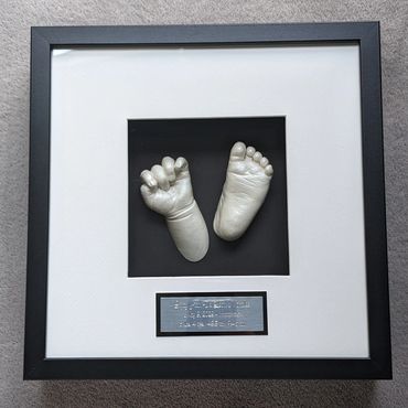 Pearl coloured baby hand and foot casting in a square shadow box with black and silver name plate