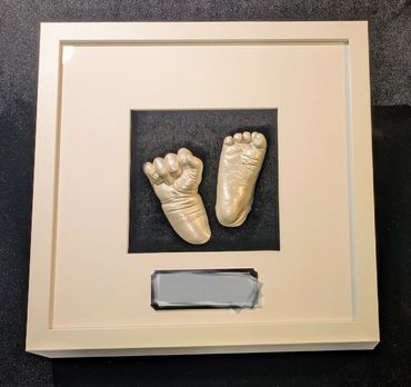Pearl coloured baby hand and foot casting in a square shadow box with black and silver name plate