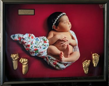 Golden baby hand and foot castings displayed in a shadow box with baby photo
