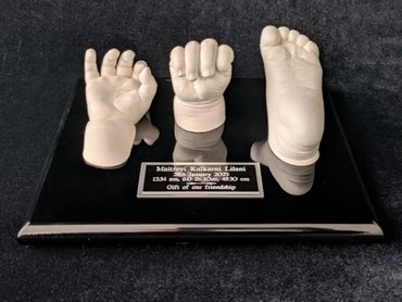 6 month old baby hands and foot casts displayed on a black plaque.