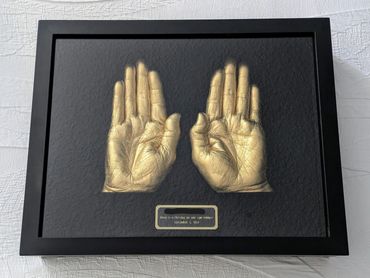 Shiny gold adult woman's hand casts displayed in a black shadow box with black & gold name plate