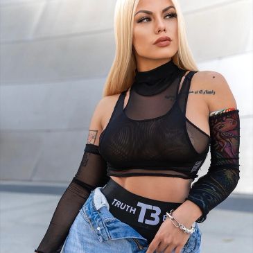 Blonde woman in black mesh top and denim shorts.