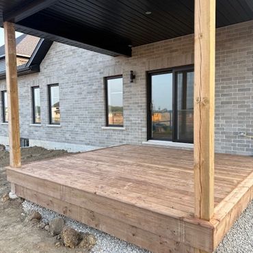 Newly built wooden deck attached to a modern brick house.