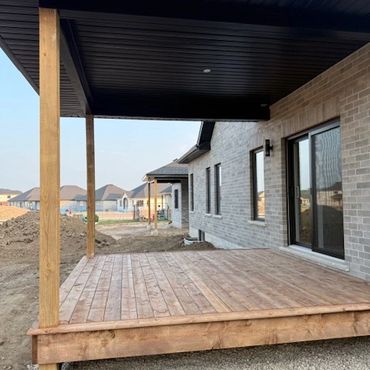 Wooden deck attached to a modern brick house under a clear sky.