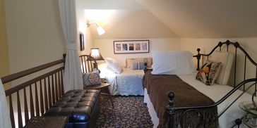 Cozy attic room with twin beds and warm lighting.
