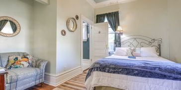 Ophelia Suite, green room, queen bed, natural lighting.