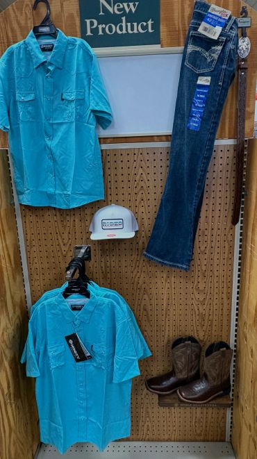 Clothing display with turquoise shirts, jeans, hat, and boots.
