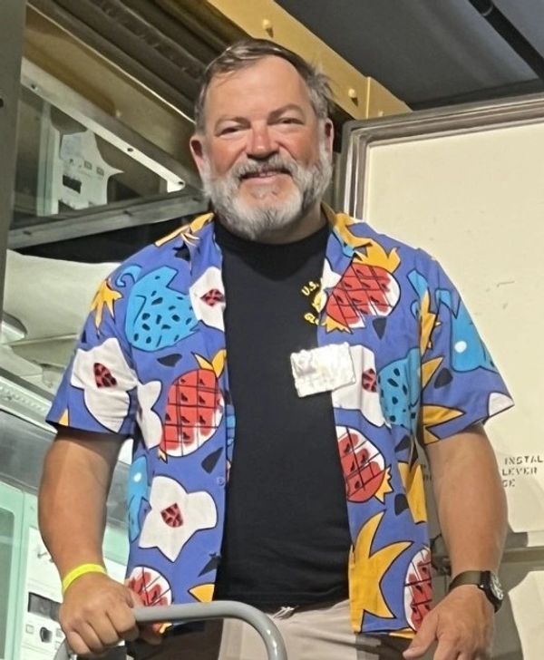 Smiling man in a colorful pineapple shirt.