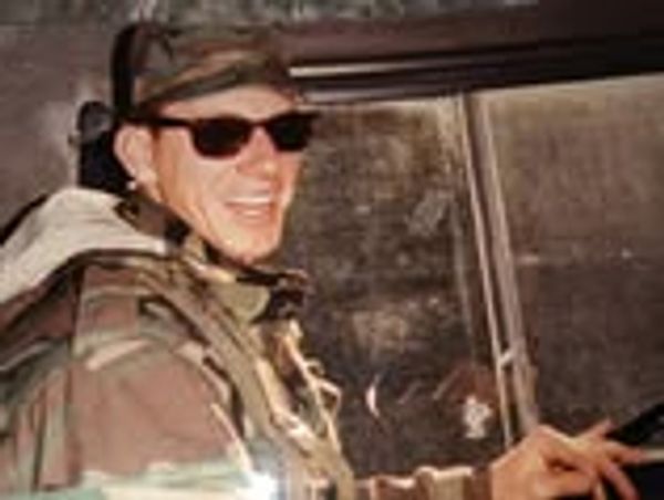 Smiling soldier in camouflage and sunglasses.