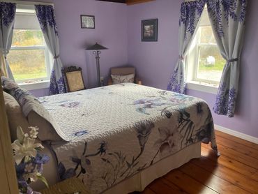 Between the windows with curtains bearing the lavender flower, you can sit down and read a book.