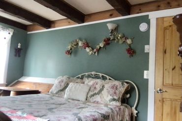 Above the Queen bed with wrought-iron headboard, is a decor swag beneath the exposed beams.