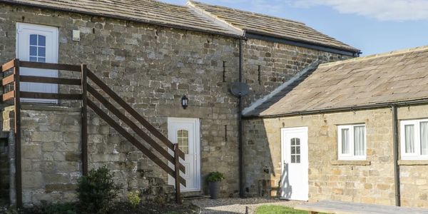 Stone house with white doors and outdoor staircase under a blue sky.