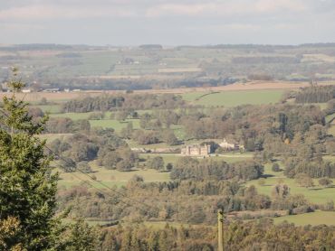 Scenic countryside with rolling hills and a large estate in the middle.