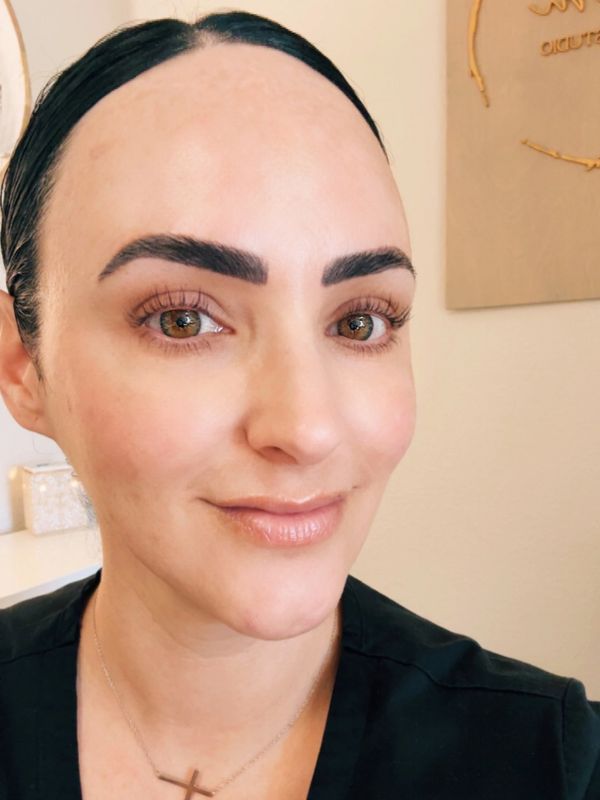 Close-up of a woman with neatly groomed eyebrows and a cross necklace.