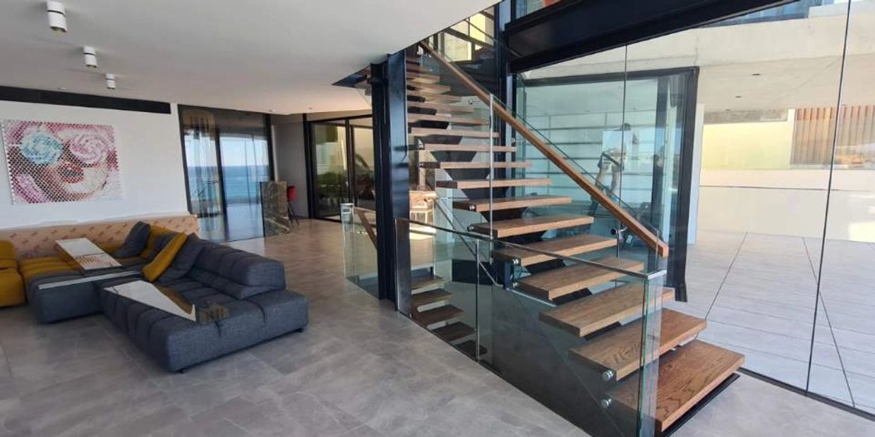 Internal timber stair case with a glass balustrade.  Living room with pop art on the wall.