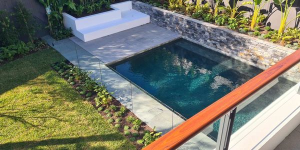 View over a glass balustrade looking down onto a pool with a frameless glass fence.  