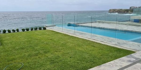 Pool with frameless glass fence overlooking the ocean.