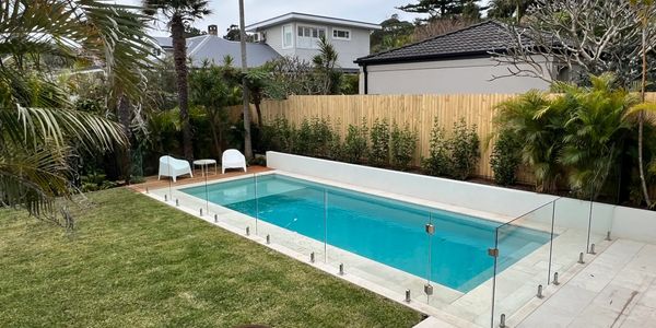 Pool with frameless glass fence.  Grassed area with fire pit.