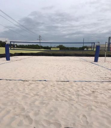 Empty sand volleyball court under cloudy sky.