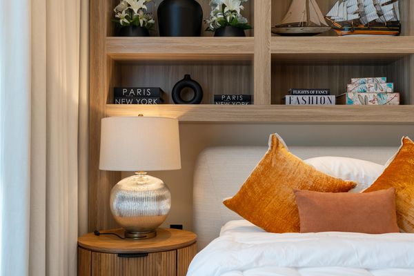 Cozy bedroom corner with warm orange pillows and a glowing bedside lamp. Premium studios Dubai, Property investment Dubai, Short-Term rental Dubai 