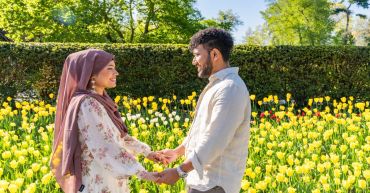 Couple holding hands in a flower garden.