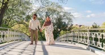 Couple holding hands walking on a bridge.
