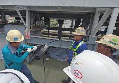 Workers in helmets and safety gear handling equipment on an industrial site.
