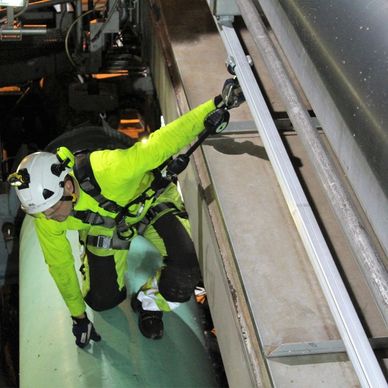 Worker in safety gear inspecting equipment overhead.