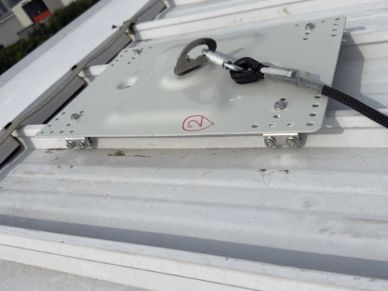 Roof safety anchor attached to metal sheet.