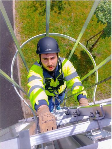 Worker climbing a ladder wearing safety gear.