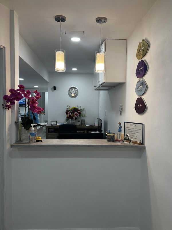 Reception desk with flowers, lights, and wall decor.