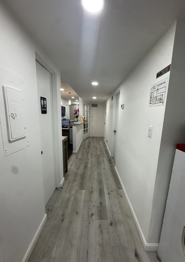 Long hallway with light wood flooring and white walls.
