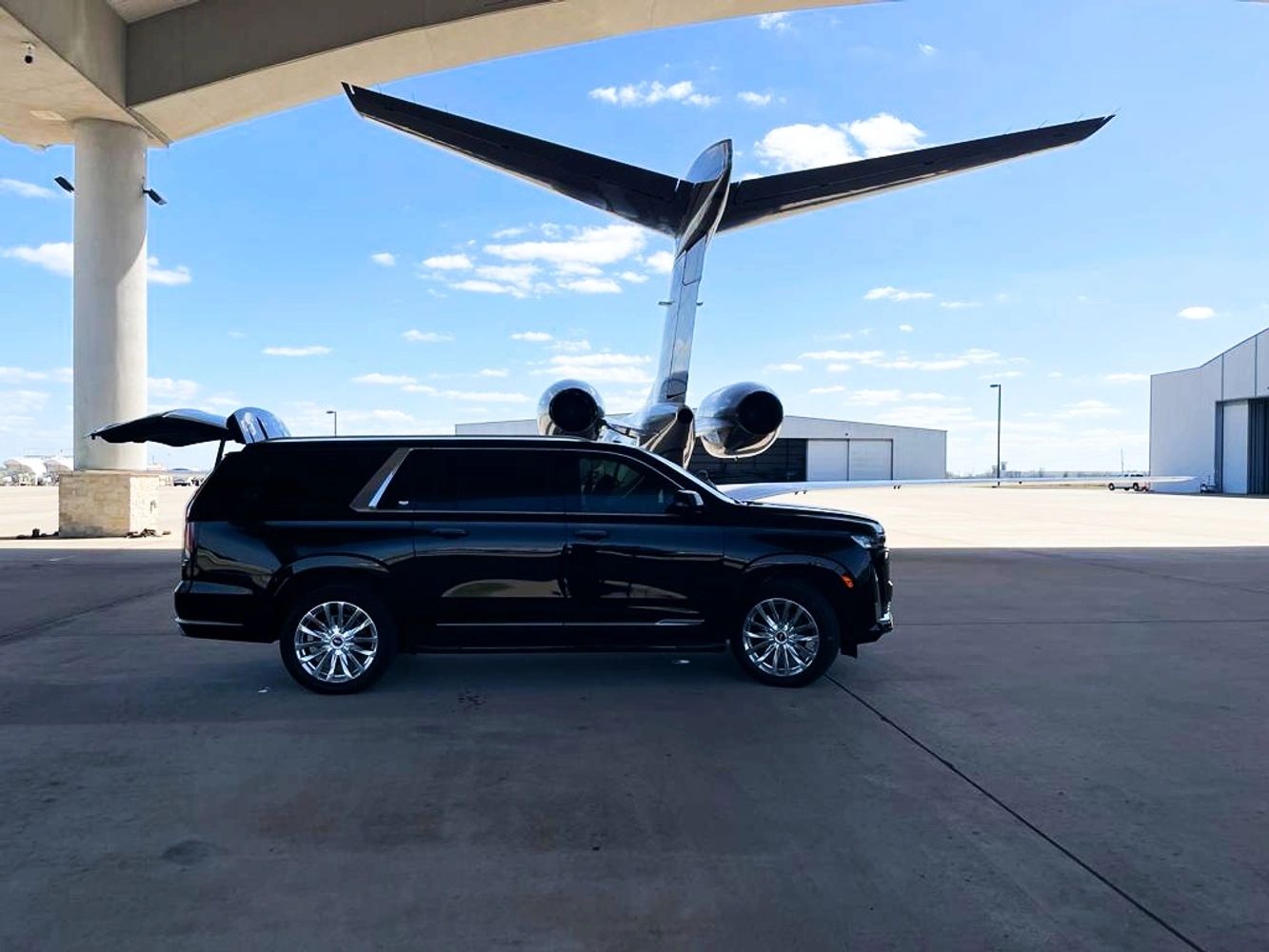 A black SUV parked in front of a large private jet on a sunny day.