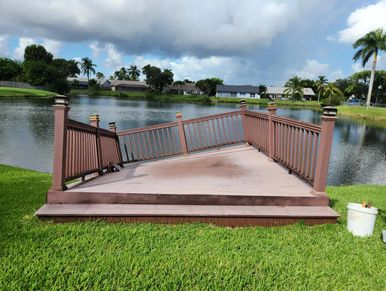 Damaged wooden deck railing leaning inward beside a lake.