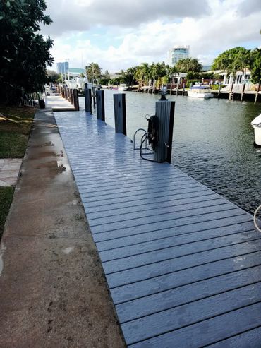 A clean dock alongside a calm waterway with boats moored nearby.