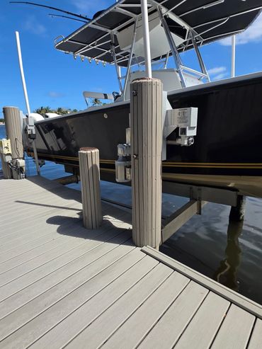 A black boat docked at a marina under a bright blue sky.