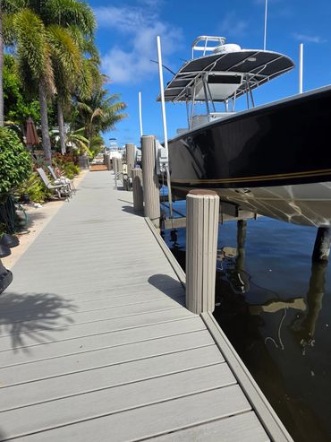 Boat docked beside a sunny, palm-lined walkway.