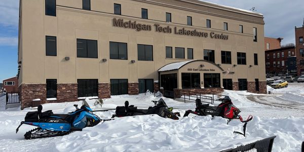 Snowmobiles parked outside Michigan Tech Lakeshore Center in winter.