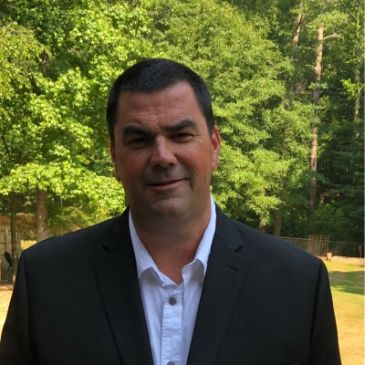 Man in a suit standing outdoors.